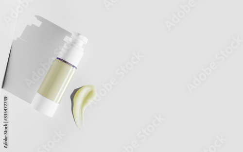 Top view of organic skincare plastic dispenser bottle with cream moisturizer smear on light background. Sample beauty products for facial skin care. Health and beauty. Close-up. Copy space