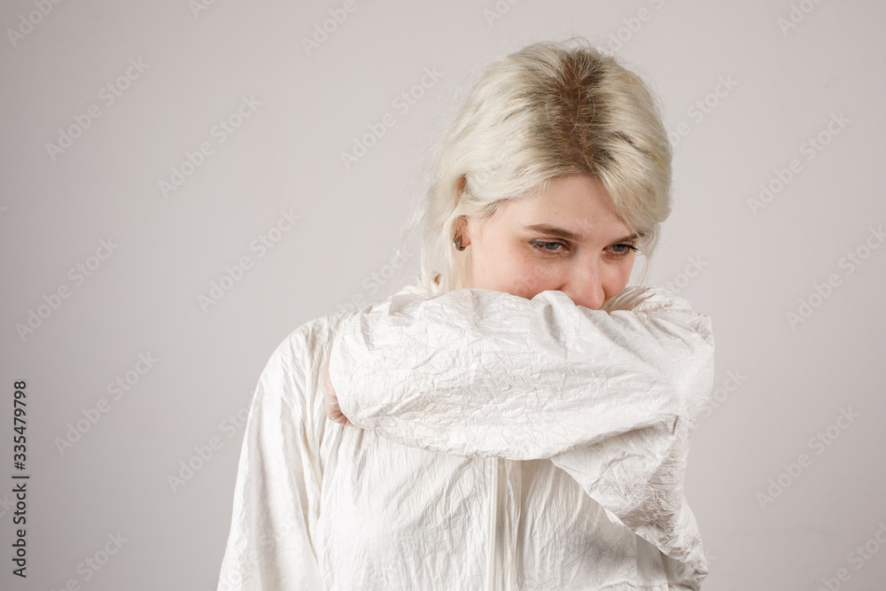 The girl sneezes into the bend of the elbow to prevent the spread of airborne droplets. New Covid-19. Corona virus pandemic concept. Stop the virus. Hygiene. Close-up. The girl sneezes into the bend of the elbow to prevent the spread of airborne droplets. New Covid-19. Corona virus pandemic concept. Stop the virus. Hygiene. Close-up.