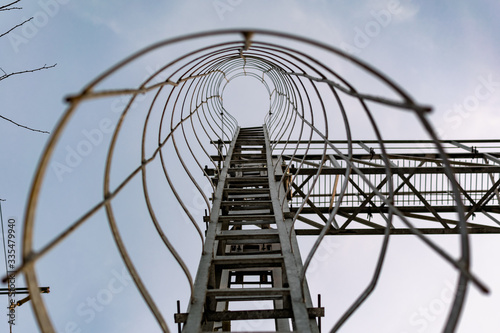 A metal structure made of thin but strong rings , chained together in a high tower stand for elevation to the top, covered with gray paint