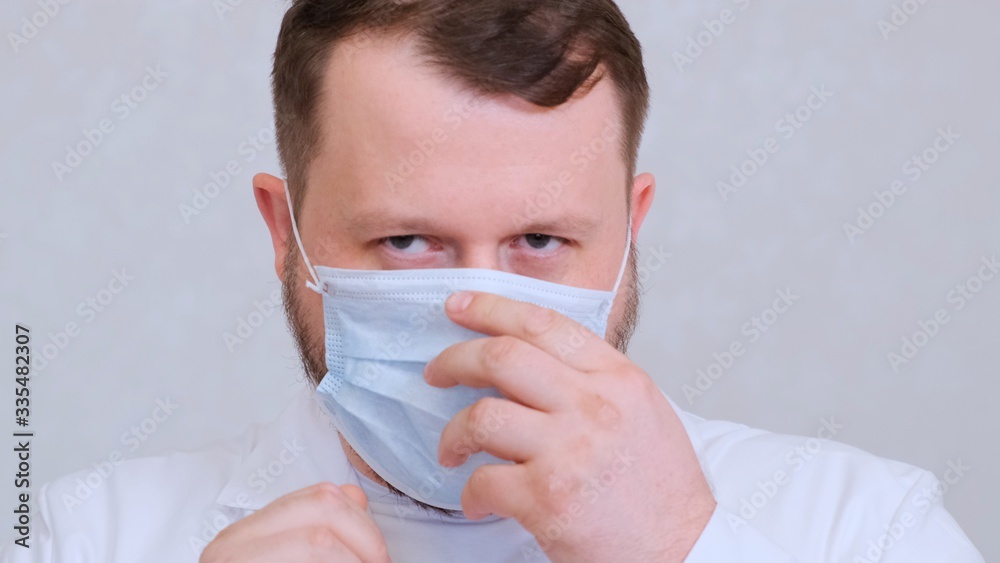 Male in a protective mask and a white shirt looks at the camera, close-up. Hygiene concept. prevent the spread of germs and bacteria and avoid infection with the crown virus. copy space