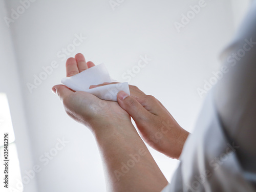 Woman cleaning her hands with a wet wipes on a white background photo