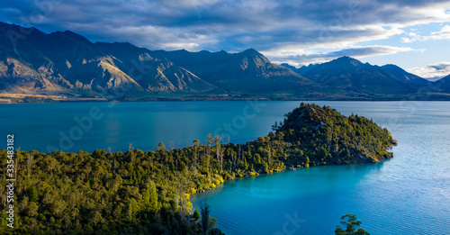 Green lush Forest peninsula on Lake Wakatipo with Southern Alps mountains in the background, aerial view at sunset photo