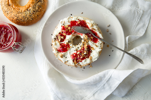 plate with bagels with cream cheese and raspberry jam on a light table