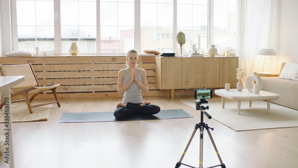 Attractive Caucasian recording making live stream or vlog about doing yoga at home. Stay home, quarantine workout