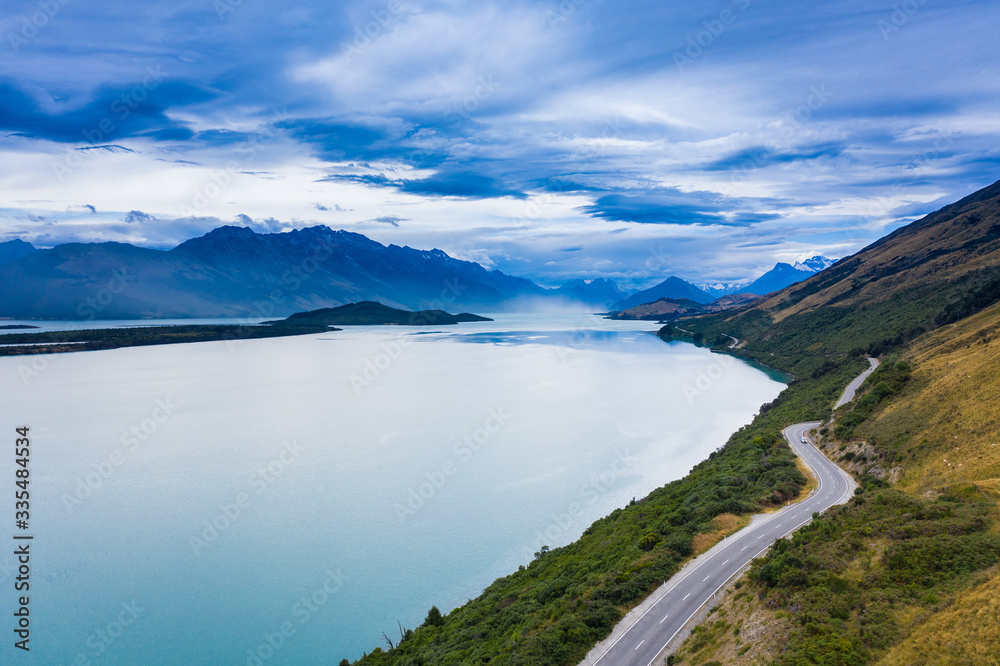 Picturesque scenic drive on winding road from Queenstown to Glenorchy by the Lake Wakatipu on a sunny day.