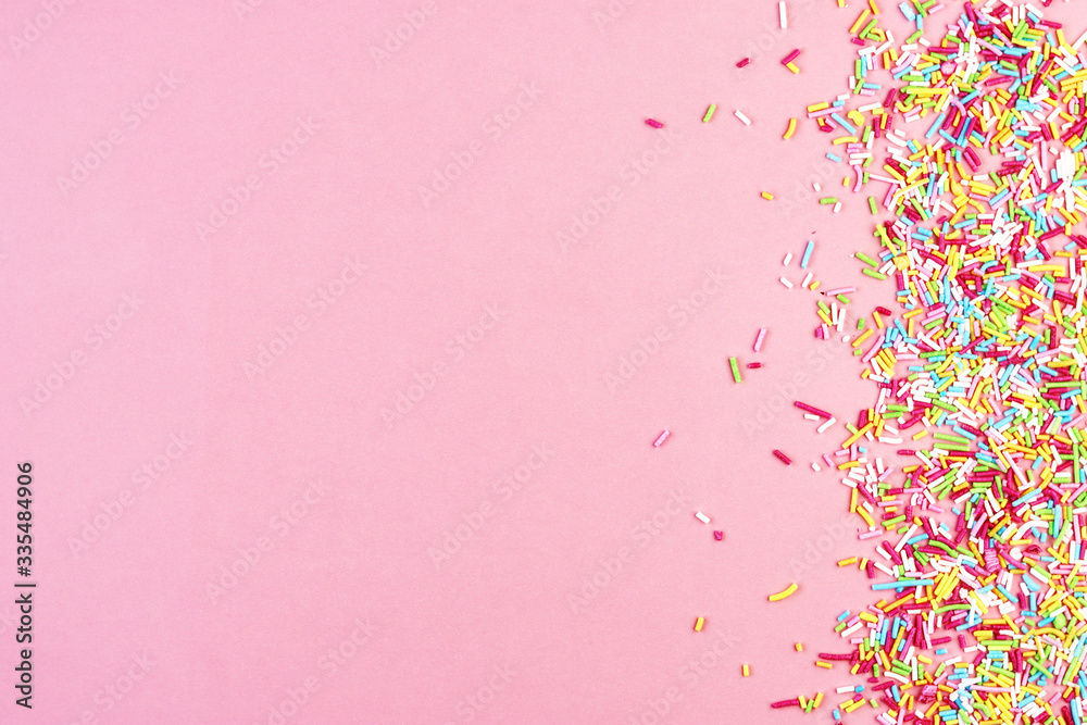 culinary pastry rainbow sprinkles are scattered on a pink background