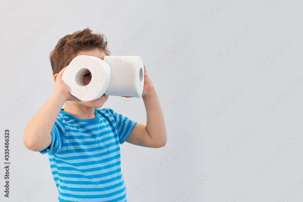 Fototapeta premium Active boy playing with toilet paper in retro filter,kid boy looking through toilet roll,Child holding two white tissue, looking through toilet paper like binoculars