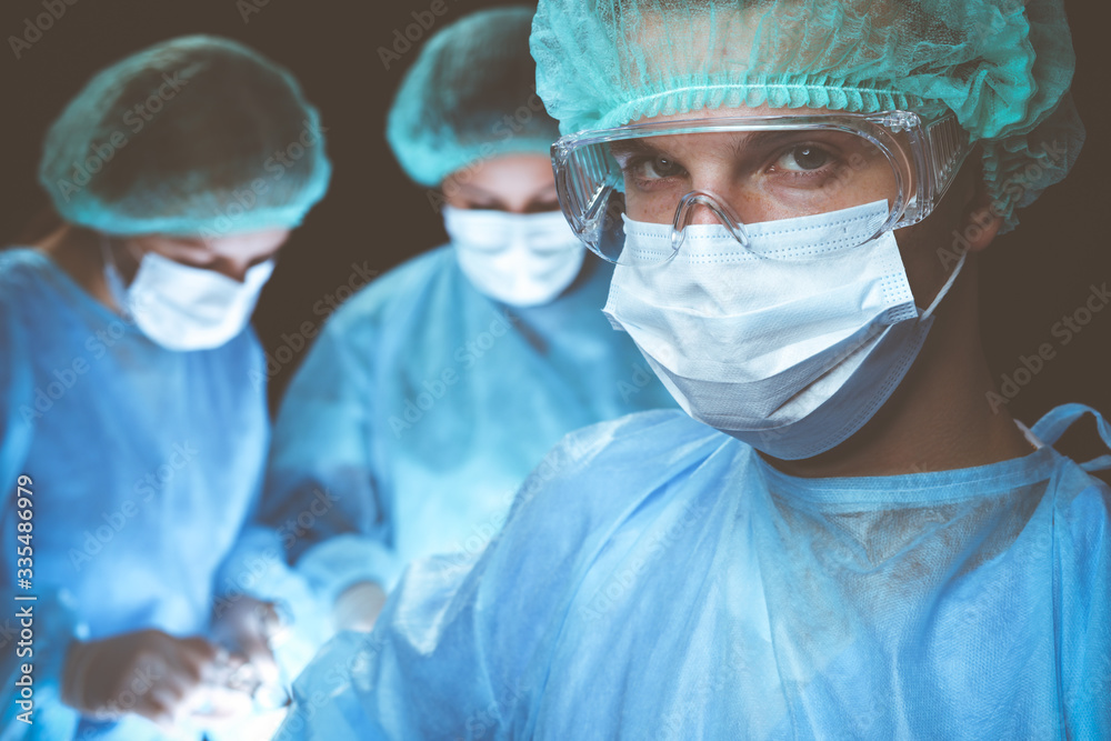 Group of surgeons wearing safety masks performing operation. Medicine concept Group of surgeons wearing safety masks performing operation. Medicine concept