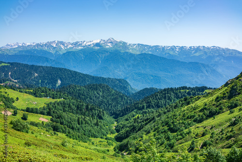 View over the Green Valley, surrounded by high mountains with snow on a clear summer day. © Dmitrii Potashkin