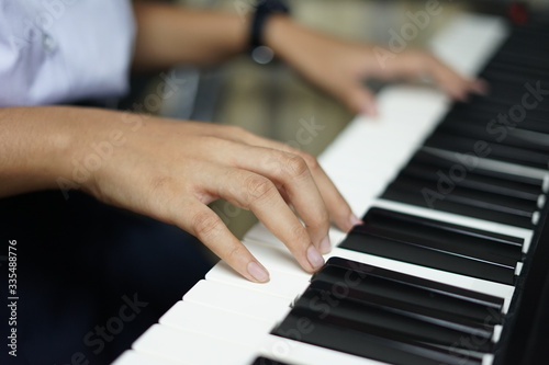 close up of the hands of girl on the keyboard of the piano