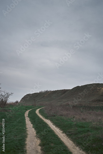 dramatic country road in the green hills mountains with grey sky. Dnieper Bug Canal Ukraine