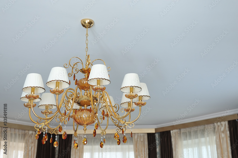 A large classic gold-colored chandelier against a white ceiling. A large classic gold-colored chandelier against a white ceiling.