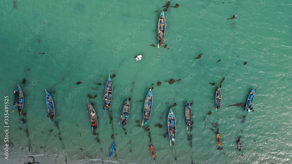 Aerial top down view of fishing long tail boats moored to the sea shore on island Koh Samui, Thailand. Fisherman village. Sunny day, azure water. Nature. Background. Wallpaper. Drone photography.