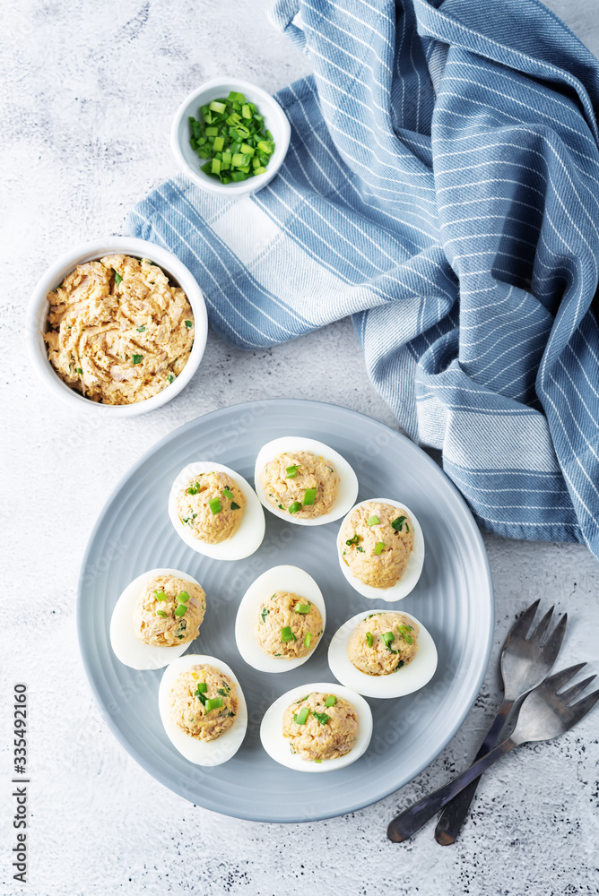 Canned Tuna deviled eggs with scallion on a light background