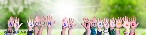 Children Hands Building Colorful English Word As Soon As Possible. Sunny Green Grass Meadow As Background