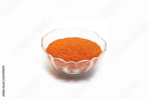 Powder red chilies in glass pot on white background