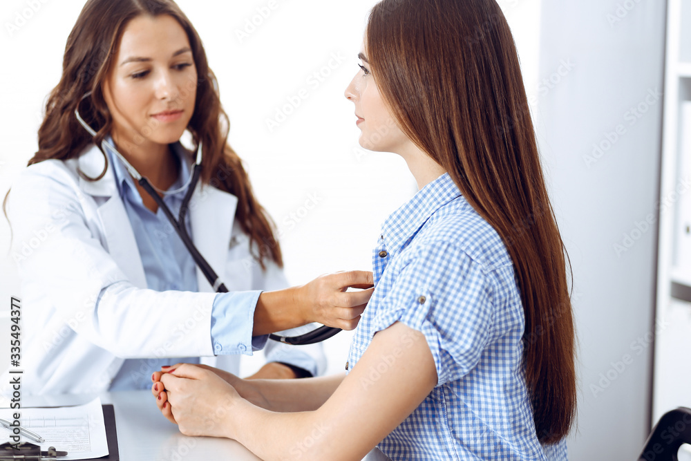 Doctor with a stethoscope in the hand examining her female patient. Health care, cardiology and medicine concepts Doctor with a stethoscope in the hand examining her female patient. Health care, cardiology and medicine concepts