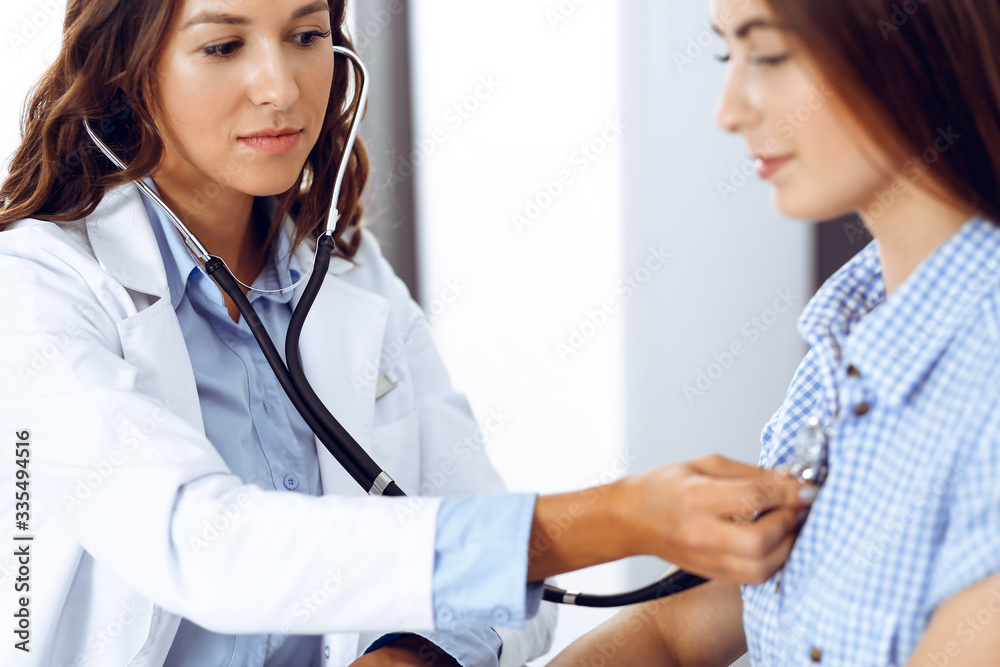 Doctor with a stethoscope in the hand examining her female patient. Health care, cardiology and medicine concepts Doctor with a stethoscope in the hand examining her female patient. Health care, cardiology and medicine concepts