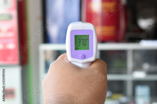 holding hand thermometer scanner in shop before entry