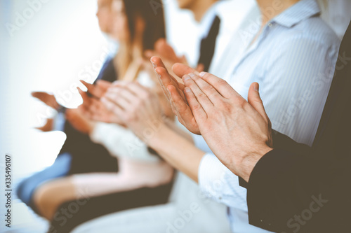 Business people clapping and applause at meeting or conference, close-up of hands. Group of unknown businessmen and women in modern white office. Success teamwork or corporate coaching concept