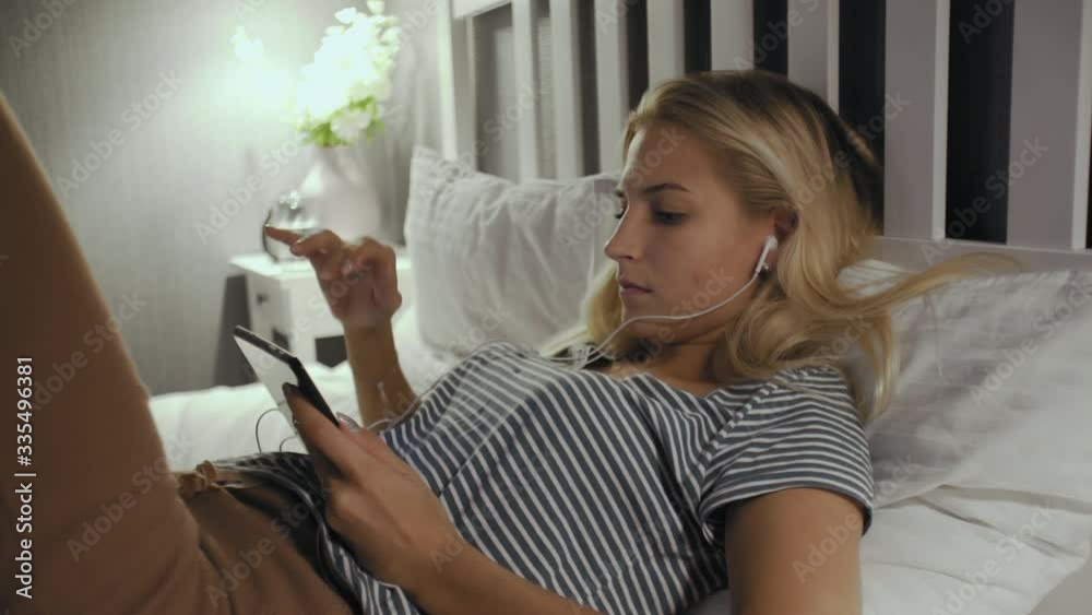 Serious teen browsing and watching media in a tablet lying on a bed at home Serious teen browsing and watching media in a tablet lying on a bed at home