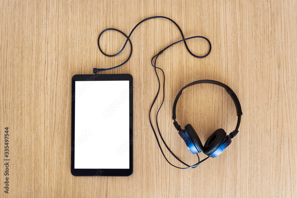 Top view of mockup tablet screen with blank content. Technology and music concept. Headphones and white screen phone copy space. Musical playlist, online music and new technologies lifestyle. Top view of mockup tablet screen with blank content. Technology and music concept. Headphones and white screen phone copy space. Musical playlist, online music and new technologies lifestyle.