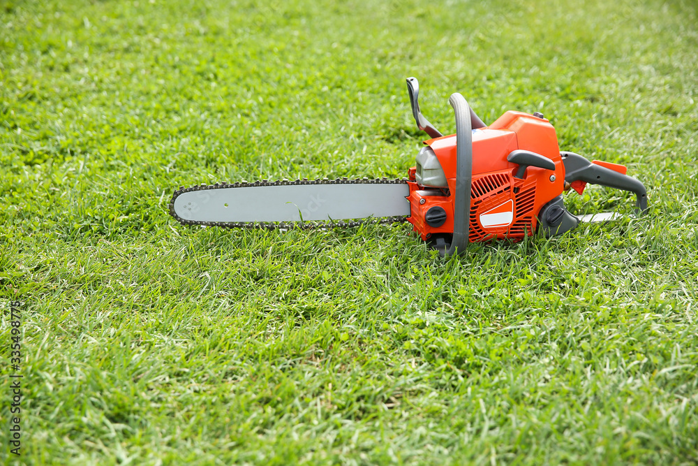  orange chainsaw on grass close up with copy space.