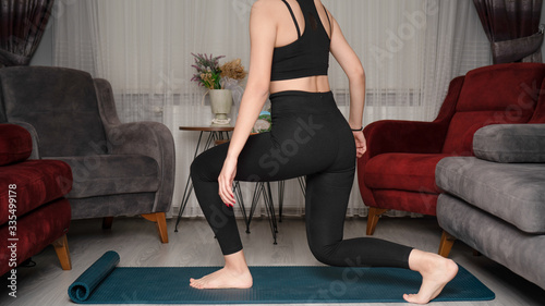 Young woman does exercises from home during quarantine time at coronavirus. 