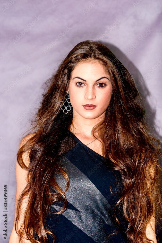 black hair woman portrait with brown eyes on a gray background , Caucasian ethnic group is looking into the camera with a serious expression on her face. White girl with long black hair and brown eye black hair woman portrait with brown eyes on a gray background , Caucasian ethnic group is looking into the camera with a serious expression on her face. White girl with long black hair and brown eye