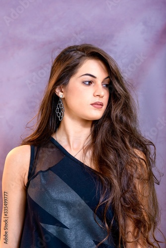 black hair woman portrait with brown eyes on a gray background , Caucasian ethnic group is looking into the camera with a serious expression on her face. White girl with long black hair and brown eye