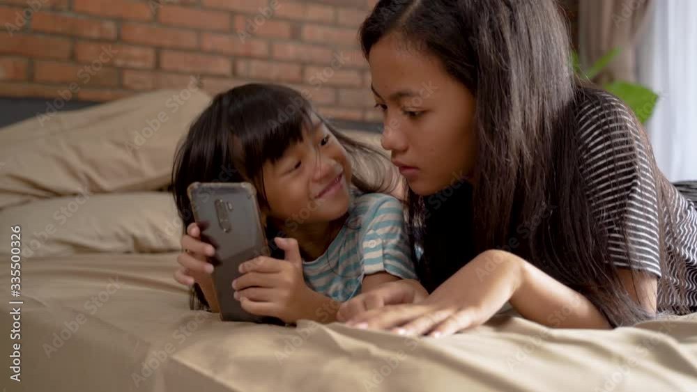 cute sibling using mobile phone together while relaxing at home cute sibling using mobile phone together while relaxing at home