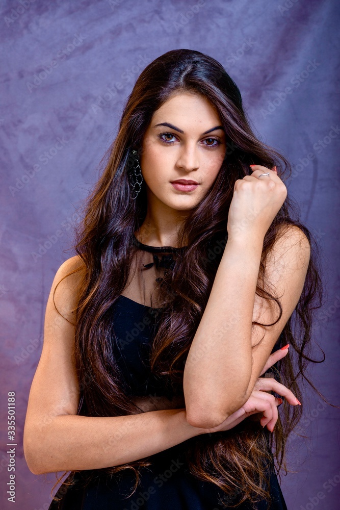 black hair woman portrait with brown eyes on a gray background , Caucasian ethnic group is looking into the camera with a serious expression on her face. White girl with long black hair and brown eye black hair woman portrait with brown eyes on a gray background , Caucasian ethnic group is looking into the camera with a serious expression on her face. White girl with long black hair and brown eye