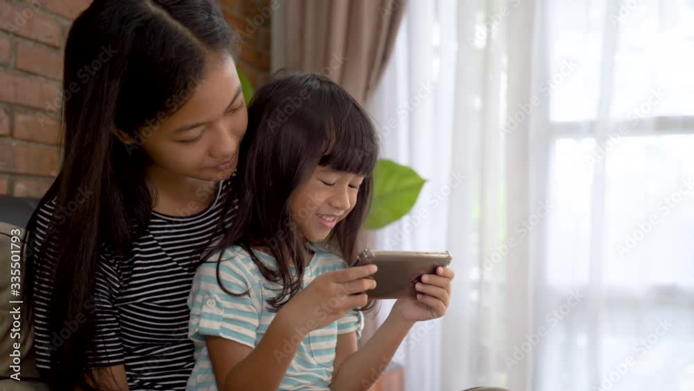 cute sibling using mobile phone together while relaxing at home cute sibling using mobile phone together while relaxing at home