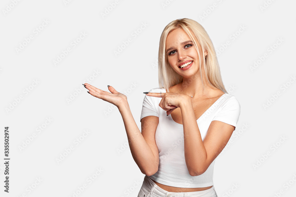 Blonde young woman showing open hand palm with copy space for product or text. Portrait of smiling pretty girl. Mockup. Blonde young woman showing open hand palm with copy space for product or text. Portrait of smiling pretty girl. Mockup.