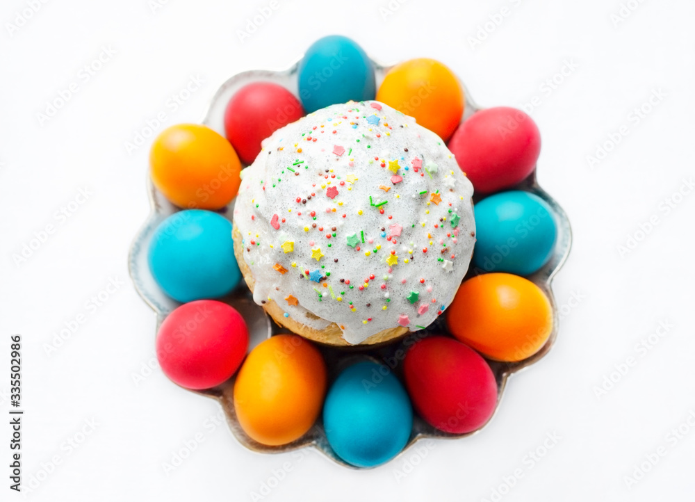 Traditional ortodox easter cake and painted eggs on a plate, top view on white