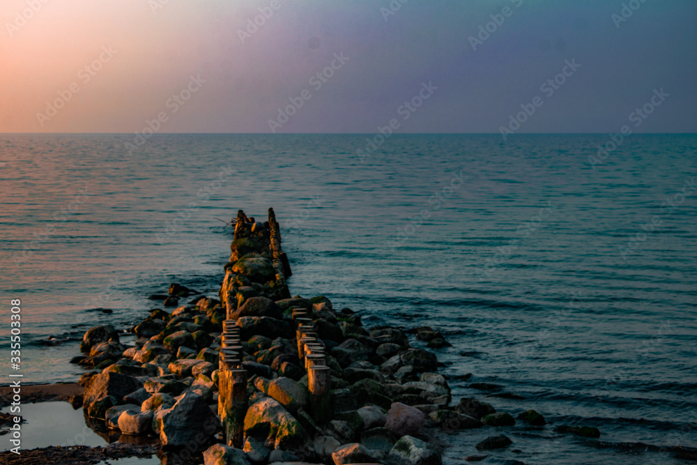 view of the sea or ocean at sunrise or sunset in quiet weather with sea stones and sand