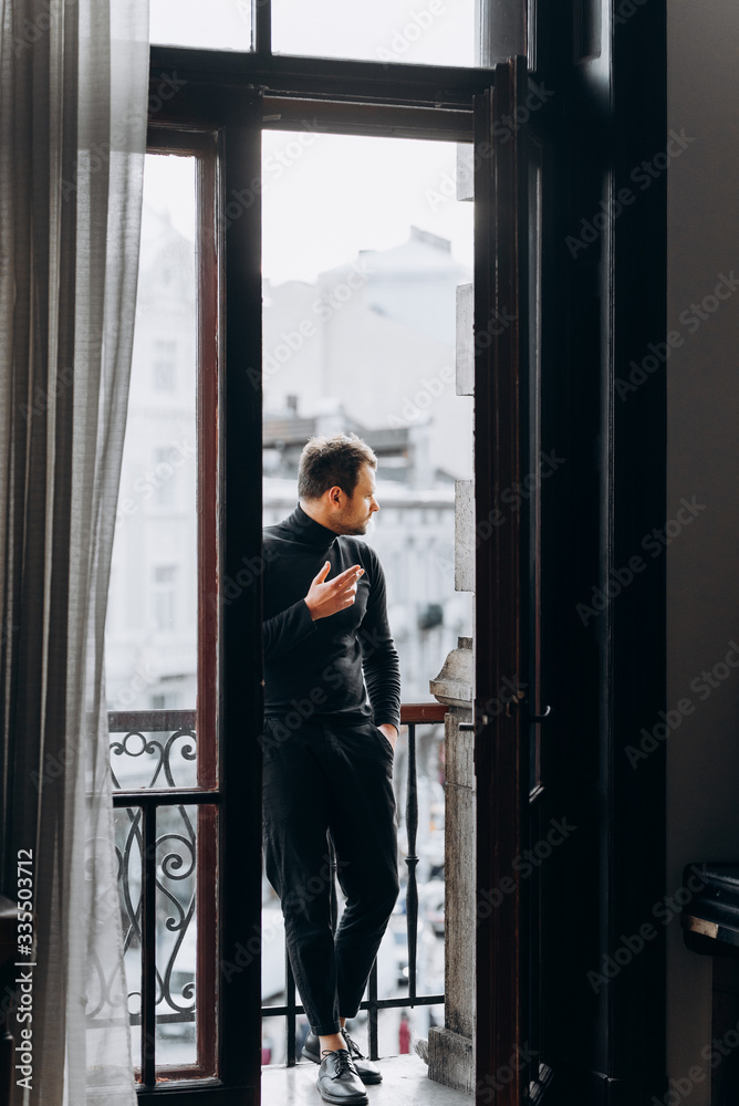 Man smokes on the balcony. The guy stands and smokes on the balcony.