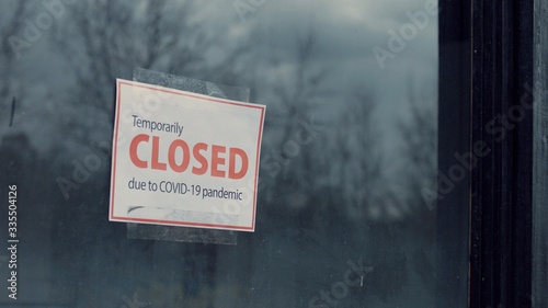 FIXED view of a Temporary closed due COVID-19 pandemic sign hanging on a window. Coronavirus pandemic, small business shutdown photo