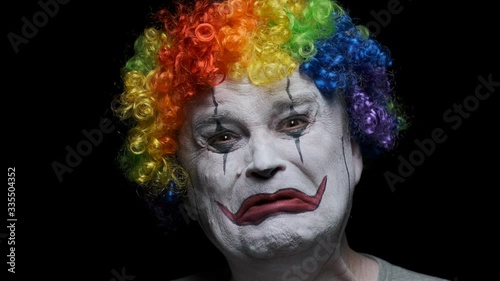 Portrait of sad clown man crying on black background. photo