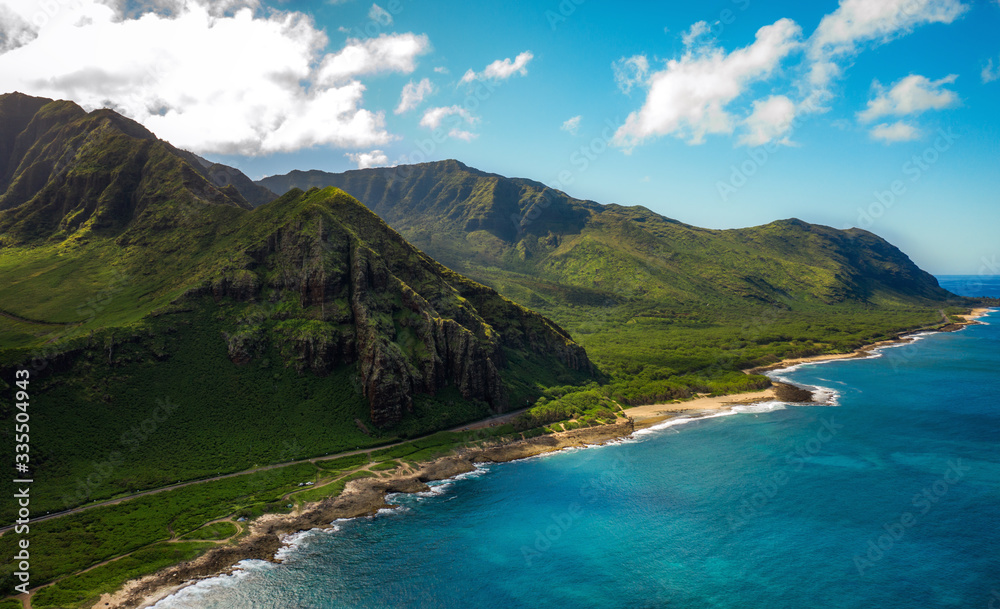 Aerial drone shot of mountains in Hawaii. Sun, clouds, shore, beach and ocean. Perfect nature from above