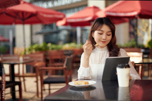Businesswoman using technologies outdoor while sitting in coffee shop.