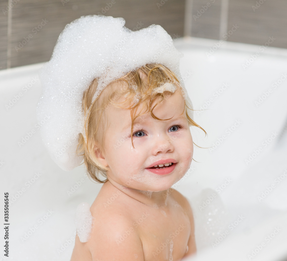 Smiling baby girl with soap suds on hair taking bath