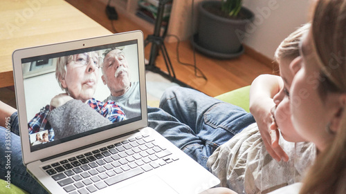 Young mom with son having a facetime video call with grandparents. Family connecting with their parents on webcam. Modern technology connecting people of all ages concept.