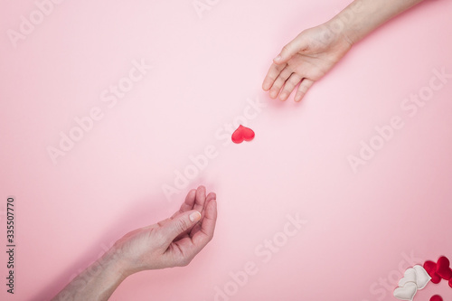 Greeting card blank on a pink background. Children and female hands hold hearts. Top view. Mother's day or Valentines day concept