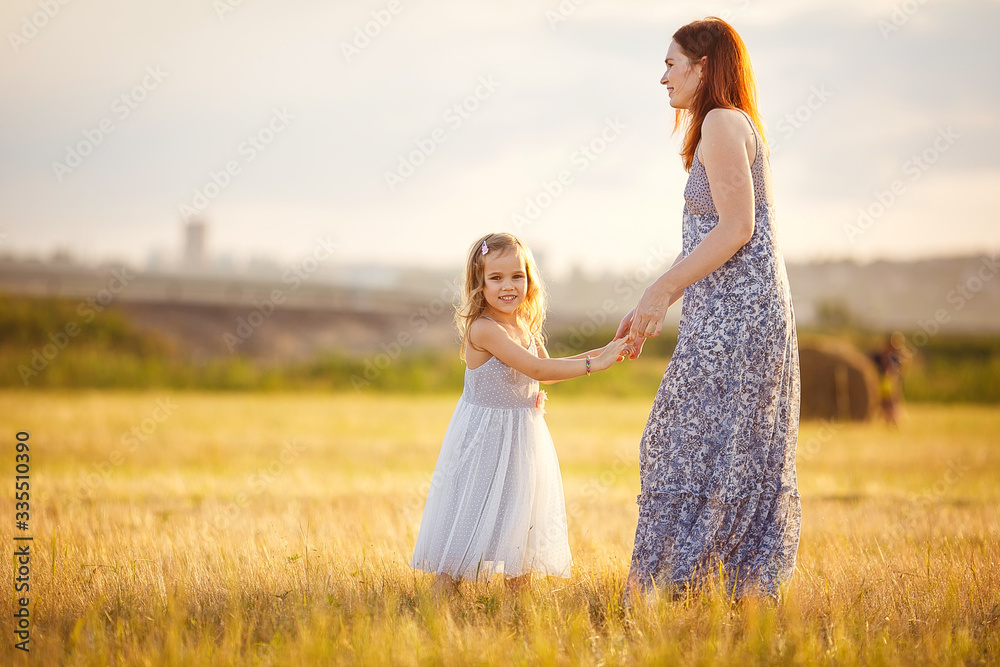 mom hold little daughter in grey dress in field mom hold little daughter in grey dress in field