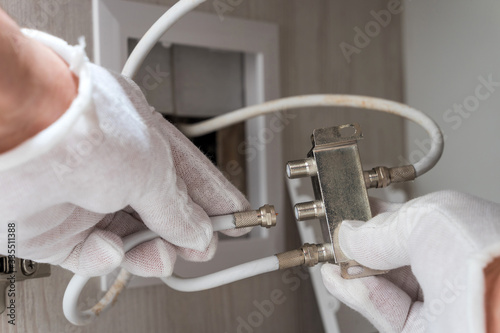 Worker inserts connector of a TV antenna coaxial cable to a splitter. photo