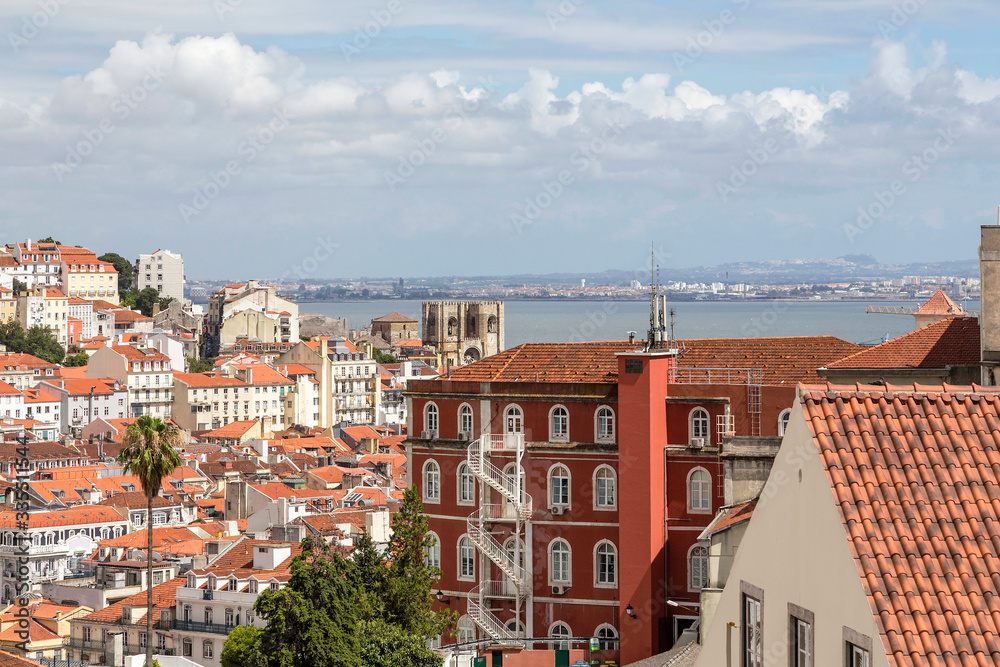 Top view on Lisbon, tiled roofs of houses and the Tagus River. Lisbon, Portugal. Summer sunny day.