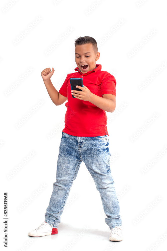 A young boy is standing with a phone and emotionally plays games or communicates on the Internet, isolated A young boy is standing with a phone and emotionally plays games or communicates on the Internet, isolated
