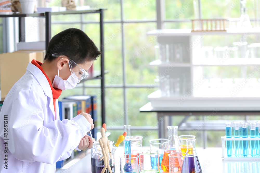 The young scientist is standing in front of his own experiment in the lab. Young kids in science lab study samples. Test for virus detection. The young scientist is standing in front of his own experiment in the lab. Young kids in science lab study samples. Test for virus detection.