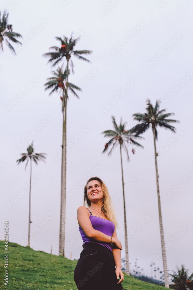 Colombia. Kokor Valley. The tallest palm trees in the world. Blonde girl stands and look at palm trees Colombia. Kokor Valley. The tallest palm trees in the world. Blonde girl stands and look at palm trees